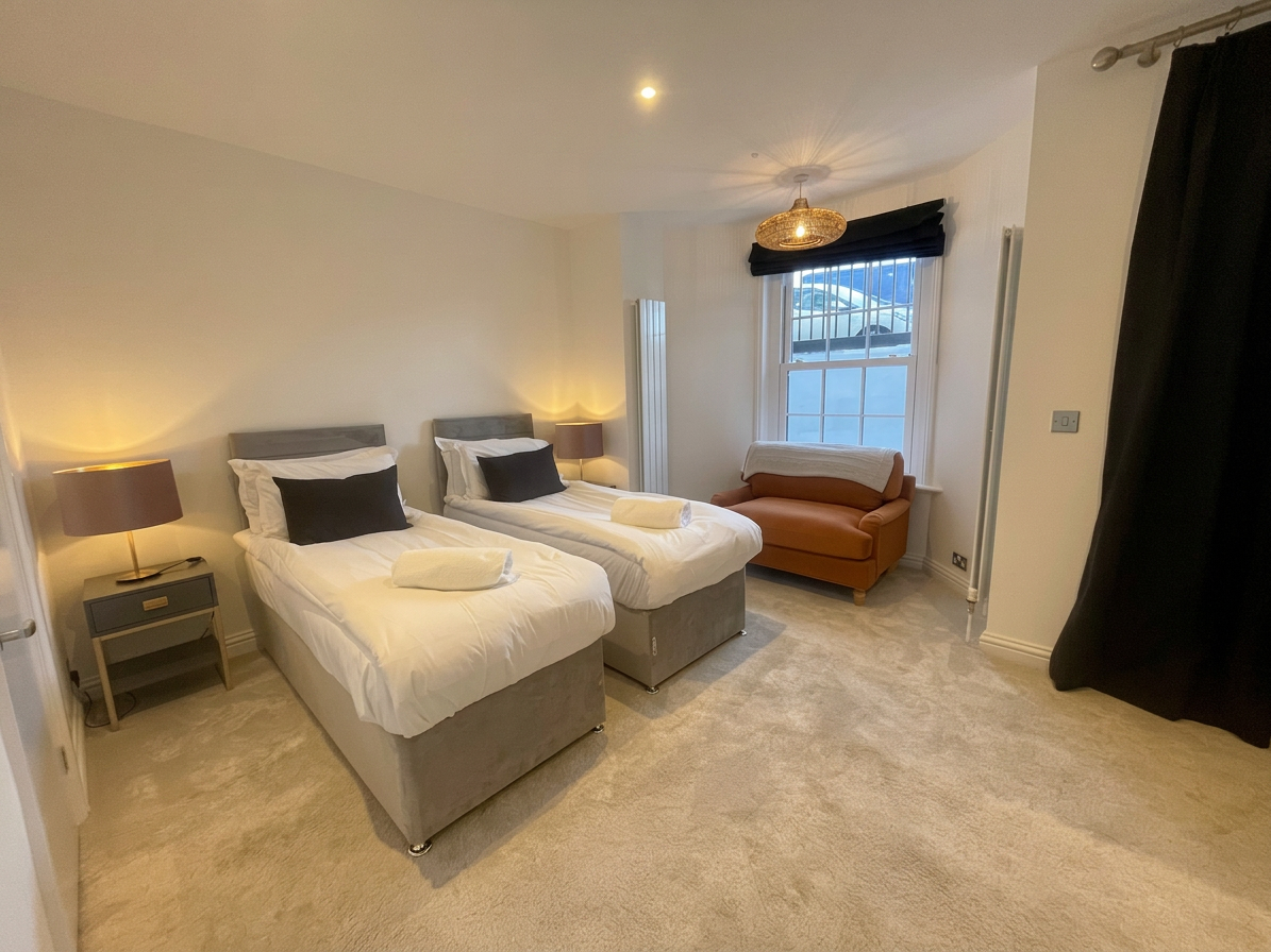 Hastings House twin bedroom with grey beds and burnt orange armchair